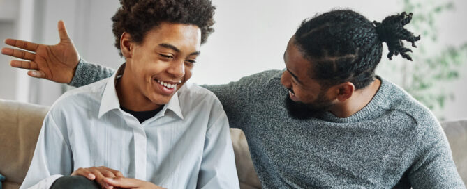 Portrait of a happy teenage boy son talking to his father at home. Sharing secrets and having fun, support and parenthood concept