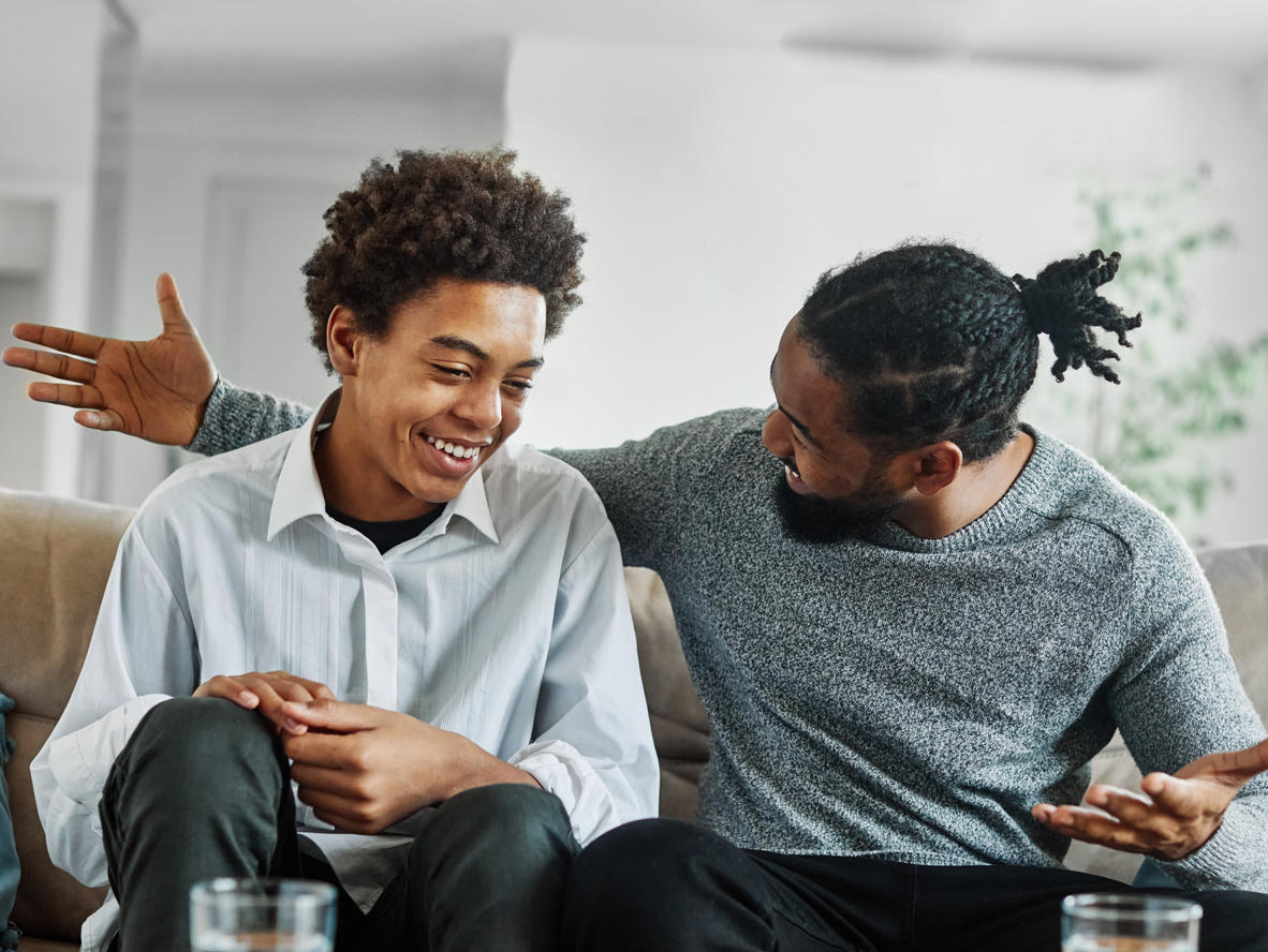 Portrait of a happy teenage boy son talking to his father at home. Sharing secrets and having fun, support and parenthood concept