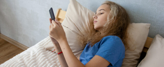 teen girl browsing social media while lying on her bed in the bedroom. Communication of modern children